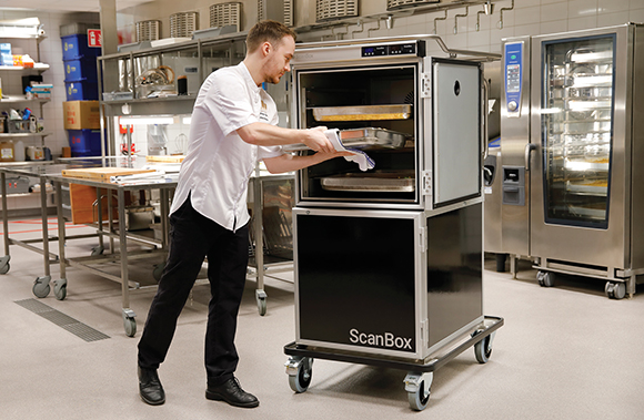 Man in kitchen placing a food pan inside of a ScanBox unit