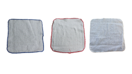 Three white wash cloths with red and green trim, neatly folded and stacked on top of each other.