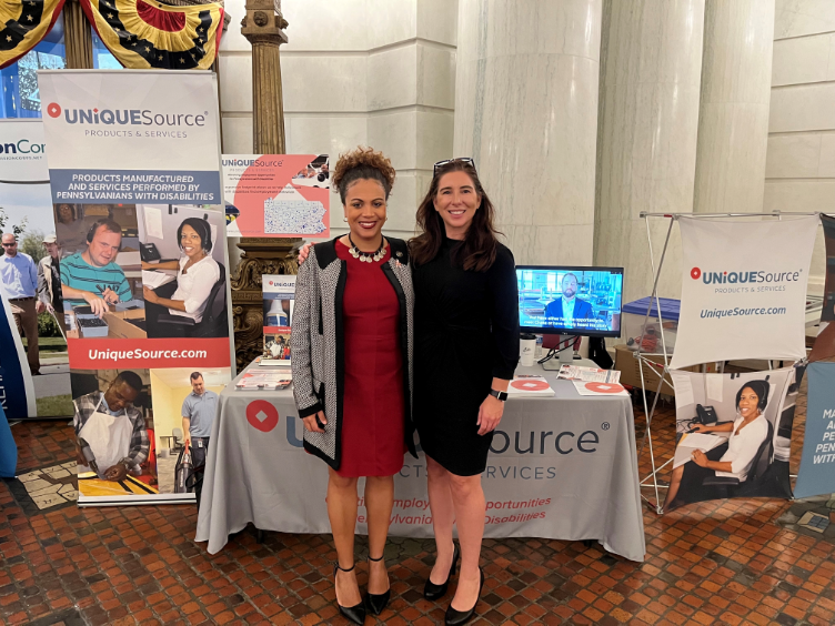 Two women standing in front of the UniqueSource table in the PA State Capitol Building.